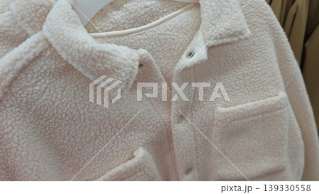 Soft fleece shirt displayed on hanger, showcasing texture and details of buttons, pockets, and collar in a retail clothing store environment Soft fleece shirt displayed on hanger, showcasing texture and details of buttons, pockets, and collar in a retail clothing store environment 139330558