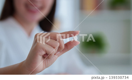 Asian women hand holding white pill tablet medicine supplement vitamin for health wellness treatment taking medication at home pharmacy healthcare medical 139330734