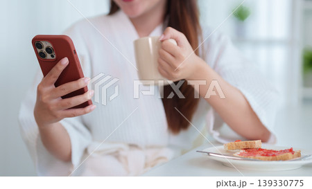 Asian women using smartphone drinking coffee eating breakfast toast jam morning routine at home relaxing happy lifestyle browsing mobile phone technology Asian women using smartphone drinking coffee eating breakfast toast jam morning routine at home relaxing happy lifestyle browsing mobile phone technology 139330775