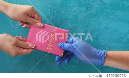 Passport control. Travel hygiene. Customs officer hand in protective glove taking female passenger id on blue copy space background. 139330938