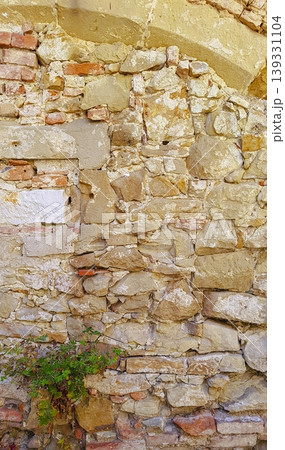 Old weathered wall combins irregular stones with ancient masonry and worn surfaces, suitable for design and background use. Old weathered wall combins irregular stones with ancient masonry and worn surfaces, suitable for design and background use. 139331104