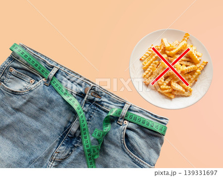 Weight loss diet control concept with jeans and fries crossed out, showing obesity risk and healthy eating choice for body shape management, slimming motivation and wellness goals. 139331697