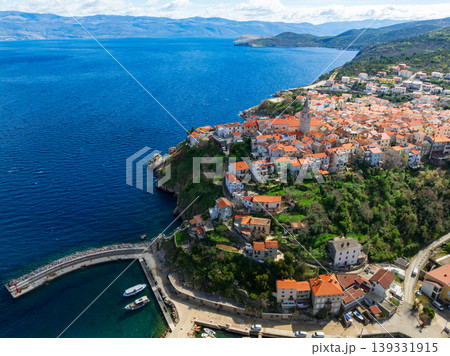 Drone captures stunning top view of Vrbnik towns on Krk Island in Croatia. Blue Adriatic Sea meets rocky coastline and traditional Mediterranean architecture from above. 139331915