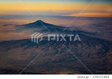 Aerial view of mountain landscape at sunset from airplane window Aerial view of mountain landscape at sunset from airplane window 139331968