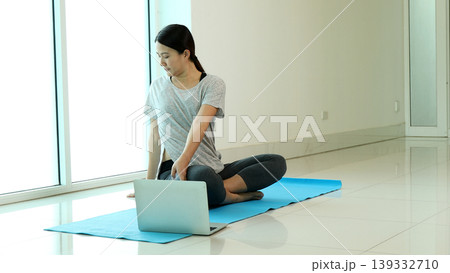Woman practicing yoga at home using laptop for online fitness class, sitting on mat and stretching body, highlighting healthy lifestyle, remote workout, digital wellness and self care routine Woman practicing yoga at home using laptop for online fitness class, sitting on mat and stretching body, highlighting healthy lifestyle, remote workout, digital wellness and self care routine 139332710