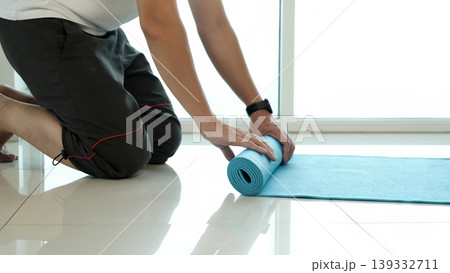 Close-up of person rolling out yoga mat on floor at home, preparing for fitness workout, stretching and wellness routine, highlighting healthy lifestyle, exercise preparation and indoor activity Close-up of person rolling out yoga mat on floor at home, preparing for fitness workout, stretching and wellness routine, highlighting healthy lifestyle, exercise preparation and indoor activity 139332711