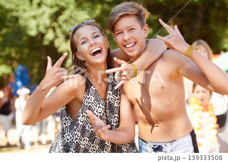 Rock, sign and teenager in portrait with friends at music festival, event or concert in summer, vacation or holiday. Happy, girl and boy hug or embrace with smile in park, woods or carnival in forest 139333508