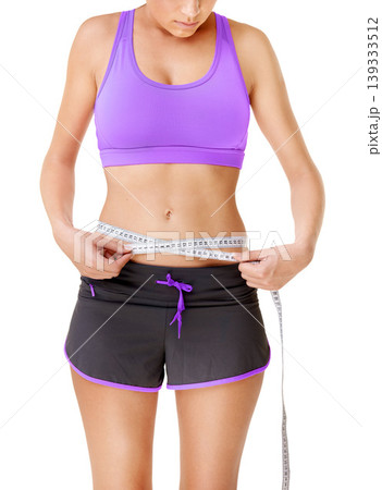 Woman, measuring tape or stomach for weight loss in studio with fitness, wellness or body progress. Person, belly or waist with target for exercise, training or workout on white background and face 139333512