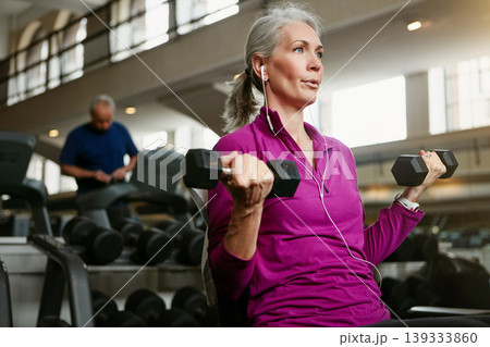 Dumbbell, fitness and senior woman at a gym for training, wellness and cardio with earphones, music or mindset. Weightlifting, bodybuilding and elderly female person at sports center for arm workout 139333860