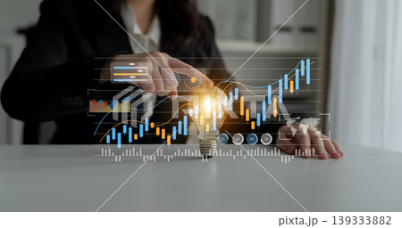 Business person analyzing financial growth by touching a light bulb with graphs and data charts displaying progress in the background Gantry Business person analyzing financial growth by touching a light bulb with graphs and data charts displaying progress in the background Gantry 139333882