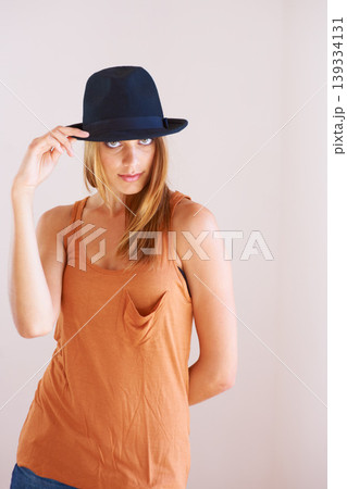 Fashion, portrait and woman with hat in studio for fancy or confidence with cool outfit on wall background. Face, attitude or female model pose with bowler, clothes or vintage and retro style 139334131