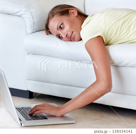 Woman, couch and laptop for movie in home, scroll and relax with reading, ideas and thinking. Girl, person and lying on sofa, choice or click in living room, floor and computer to watch film in house 139334141