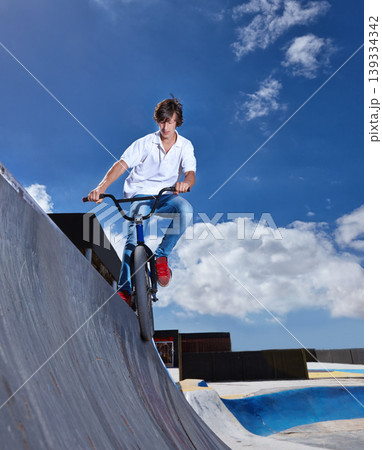 Riding, bike and teen on ramp for sport performance, jump or training for event at skatepark with sky mockup. Bicycle, stunt or kid balance on edge of board in trick for cycling competition challenge Riding, bike and teen on ramp for sport performance, jump or training for event at skatepark with sky mockup. Bicycle, stunt or kid balance on edge of board in trick for cycling competition challenge 139334342