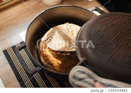 Homemade palianytsia bread baked in pot in oven. Opening cap of a pot with fresh aromatic self made bread inside Homemade palianytsia bread baked in pot in oven. Opening cap of a pot with fresh aromatic self made bread inside 139334465