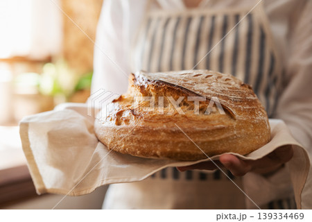 Close up of a hostess holding traditional ukrainian bread just baked from the oven. Self made bread in hands of a girl standing in kitchen 139334469