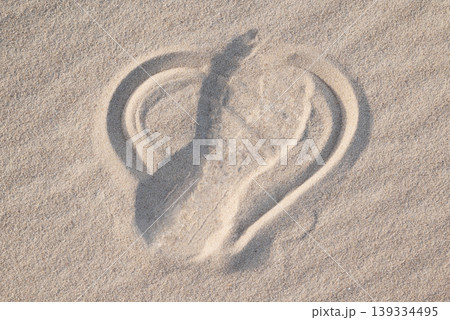 Shape of heart drawn on the sand, shoe print on it, close up. Concept of lost love, broken heart, bad emotions Shape of heart drawn on the sand, shoe print on it, close up. Concept of lost love, broken heart, bad emotions 139334495