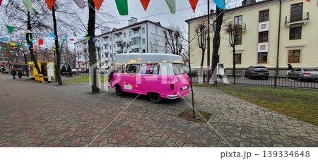 Side view of pink retro van on a cobblestone street, vintage travel aesthetic, colorful urban scene, New Year. Side view of pink retro van on a cobblestone street, vintage travel aesthetic, colorful urban scene, New Year. 139334648