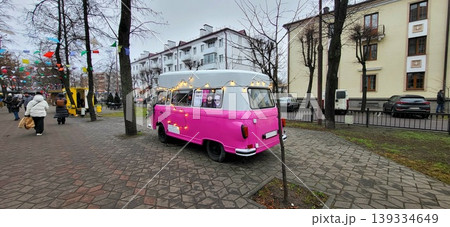 Pink vintage van parked in a historic town center, retro automotive style, colorful city travel, New Year. Pink vintage van parked in a historic town center, retro automotive style, colorful city travel, New Year. 139334649