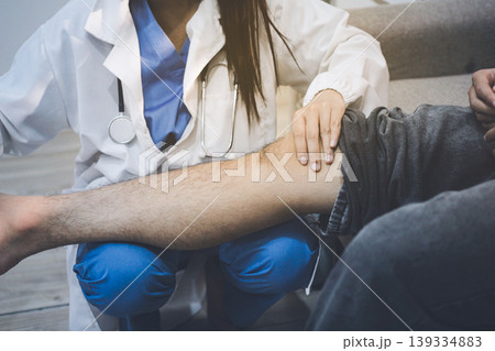 Female doctor examining male patient leg in hospital Female doctor examining male patient leg in hospital 139334883
