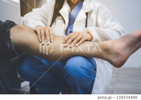 Female doctor examining male patient leg in hospital Female doctor examining male patient leg in hospital 139334886