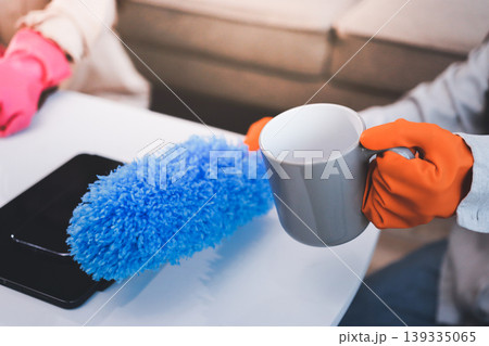 Person cleaning the room, cleaning staff is using cloth and spraying disinfectant to wipe the tables in the company office room. Cleaning staff. Maintaining cleanliness in the organization. Person cleaning the room, cleaning staff is using cloth and spraying disinfectant to wipe the tables in the company office room. Cleaning staff. Maintaining cleanliness in the organization. 139335065