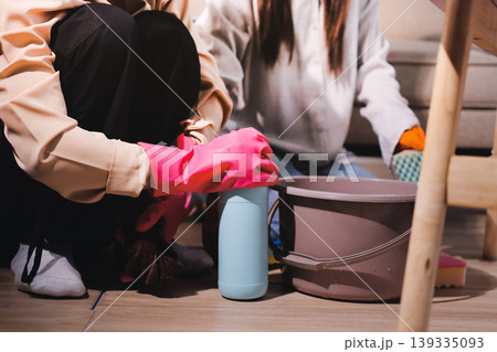 Person cleaning the room, cleaning staff is using cloth and spraying disinfectant to wipe the tables in the company office room. Cleaning staff. Maintaining cleanliness in the organization. 139335093