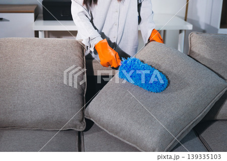 Person cleaning the room, cleaning staff is using cloth and spraying disinfectant to wipe the tables in the company office room. Cleaning staff. Maintaining cleanliness in the organization. Person cleaning the room, cleaning staff is using cloth and spraying disinfectant to wipe the tables in the company office room. Cleaning staff. Maintaining cleanliness in the organization. 139335103