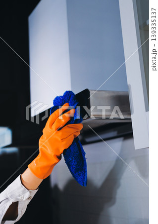 Person cleaning the room, cleaning staff is using cloth and spraying disinfectant to wipe the tables in the company office room. Cleaning staff. Maintaining cleanliness in the organization. Person cleaning the room, cleaning staff is using cloth and spraying disinfectant to wipe the tables in the company office room. Cleaning staff. Maintaining cleanliness in the organization. 139335137
