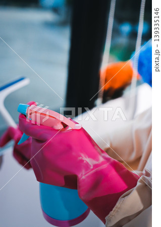 Person cleaning the room, cleaning staff is using cloth and spraying disinfectant to wipe the tables in the company office room. Cleaning staff. Maintaining cleanliness in the organization. Person cleaning the room, cleaning staff is using cloth and spraying disinfectant to wipe the tables in the company office room. Cleaning staff. Maintaining cleanliness in the organization. 139335146