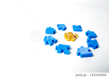 A golden puzzle piece placed in the center of several blue puzzle pieces arranged in a circle on a clean white background. Concept for business leadership, uniqueness, and finding the best solution. A golden puzzle piece placed in the center of several blue puzzle pieces arranged in a circle on a clean white background. Concept for business leadership, uniqueness, and finding the best solution. 139336908