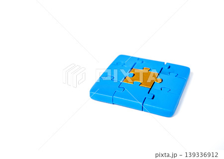 Completed square jigsaw puzzle with blue pieces surrounding a single golden center piece. Isolated on white background, representing success, leadership, and finding the perfect solution. Completed square jigsaw puzzle with blue pieces surrounding a single golden center piece. Isolated on white background, representing success, leadership, and finding the perfect solution. 139336912