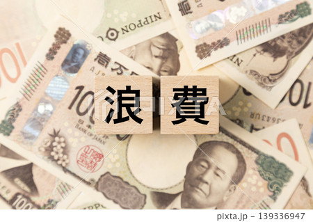「浪費」と書かれたブロックとたくさんの一万円札 「浪費」と書かれたブロックとたくさんの一万円札 139336947