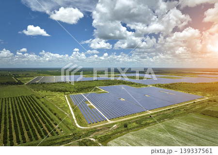 Aerial view of sustainable electric power plant between agricultural farm fields with solar photovoltaic panels for producing clean electrical energy. Renewable electricity with zero emission concept Aerial view of sustainable electric power plant between agricultural farm fields with solar photovoltaic panels for producing clean electrical energy. Renewable electricity with zero emission concept 139337561