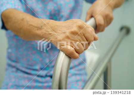Asian elderly woman patient use toilet support rail in bathroom. Asian elderly woman patient use toilet support rail in bathroom. 139341218