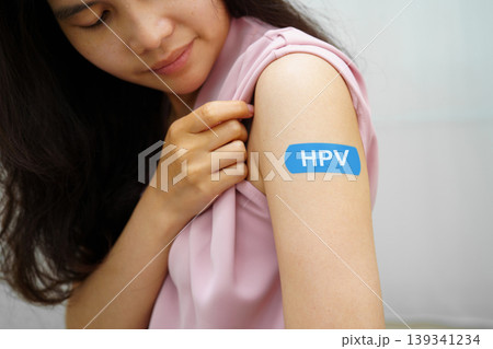 HPV, Human papillomavirus, Asian young woman receiving vaccine with blue bandage. HPV, Human papillomavirus, Asian young woman receiving vaccine with blue bandage. 139341234