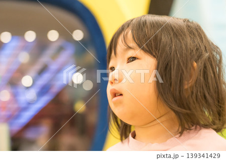 ゲームセンターのアーケードゲーム機の前に立つ日本人の女の子の幼児 139341429