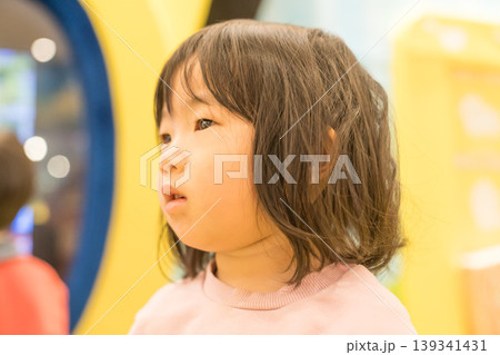 ゲームセンターのアーケードゲーム機の前に立つ日本人の女の子の幼児 ゲームセンターのアーケードゲーム機の前に立つ日本人の女の子の幼児 139341431