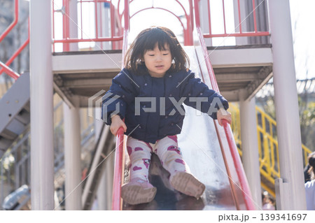 公園の滑り台を滑り降りる日本人の女の子の幼児 公園の滑り台を滑り降りる日本人の女の子の幼児 139341697