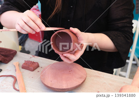 陶芸ワークショップで道具を使って手作りの陶器マグカップを成形する手 陶芸ワークショップで道具を使って手作りの陶器マグカップを成形する手 139341880