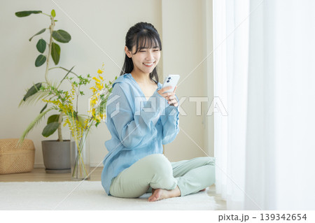 部屋でスマホを使う若い女性 部屋でスマホを使う若い女性 139342654