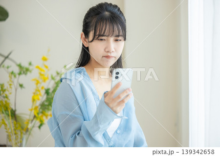 スマホを見て悩む女性 139342658