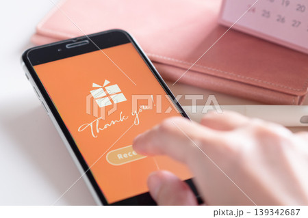 スマホに届いたソーシャルギフト (eギフト) の受け取り画面をタップする女性の手。イメージ画像 スマホに届いたソーシャルギフト (eギフト) の受け取り画面をタップする女性の手。イメージ画像 139342687