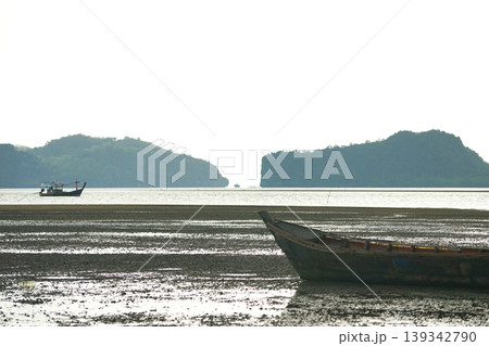 Abandoned wooden fsihing boat on the beach with seascape and space between two islands in background 139342790