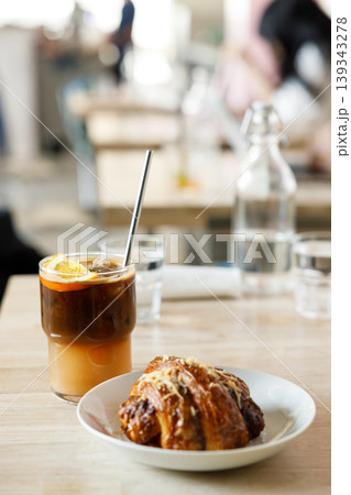 Cup of creation black coffee drink and orange juice with croissant on wooden table by the window. 139343278