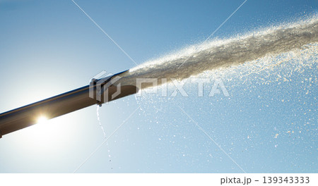 Water gushing from irrigation pipe under clear sky Water gushing from irrigation pipe under clear sky 139343333