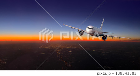 Airplane flying over city lights during sunset travel 139343583