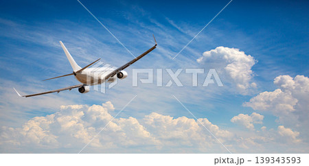 Airplane flying in clear blue sky with fluffy clouds Airplane flying in clear blue sky with fluffy clouds 139343593