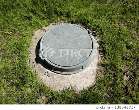 The sewer hatch is lost in the green grass 139343717