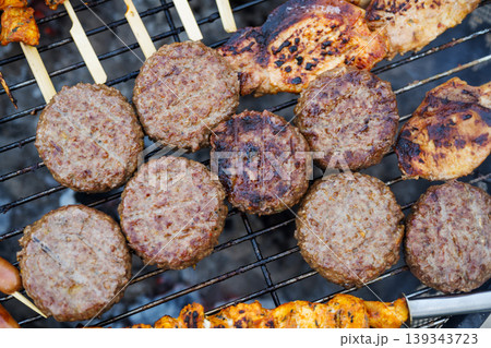 Variety of grilled meat, burgers, sausages and corn on barbecue grill outdoors, summer BBQ food cooking concept Variety of grilled meat, burgers, sausages and corn on barbecue grill outdoors, summer BBQ food cooking concept 139343723