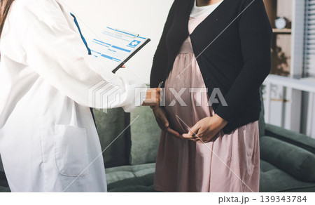 Pregnant woman having her belly examined by a doctor with a stethoscope in a clinic room highlighting a medical checkup, pregnancy health, and prenatal care Pregnant woman having her belly examined by a doctor with a stethoscope in a clinic room highlighting a medical checkup, pregnancy health, and prenatal care 139343784